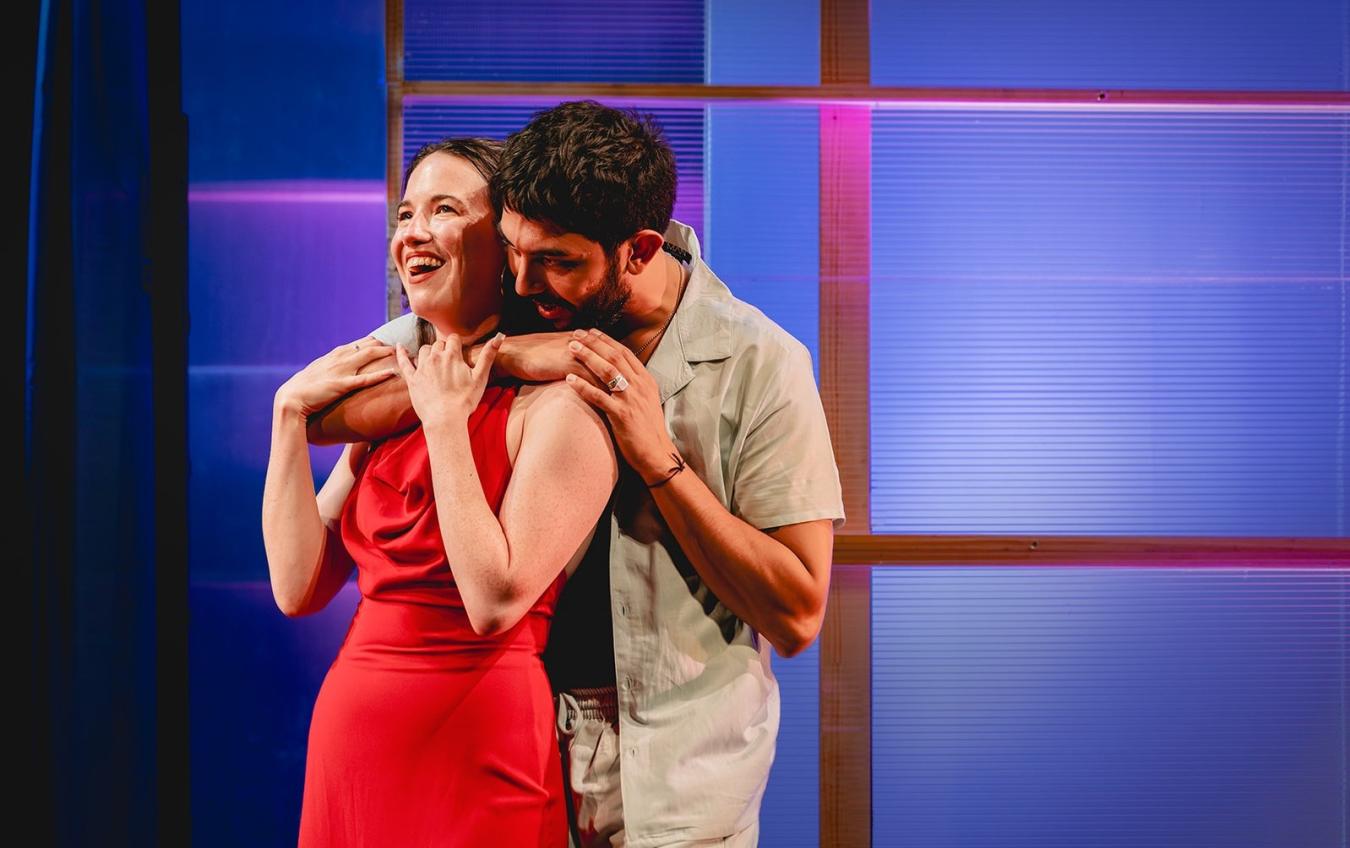 Two young actors on stage in an embrace